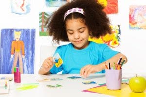 A child sits at a table with artwork on the wall behind her playing a matching card game.