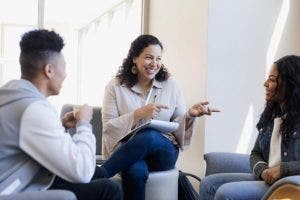 A smiling school counselor meets with two students.