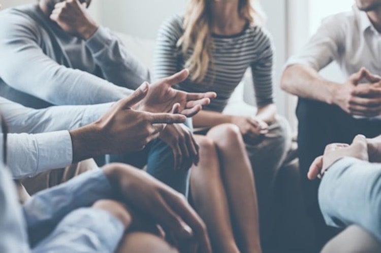 A family counselor leads a group therapy discussion.