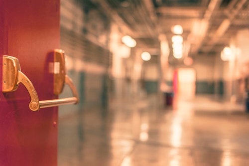 A door opens into a high school hallway.