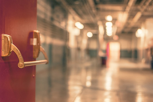 A door opens into a high school hallway.